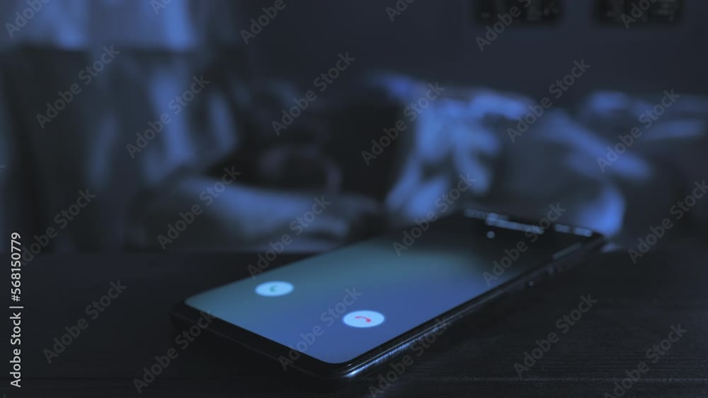 infidelity love affair,close up on mobile phone receiving incoming call while a married couple sleep on bed in the background,betrays cheating concept