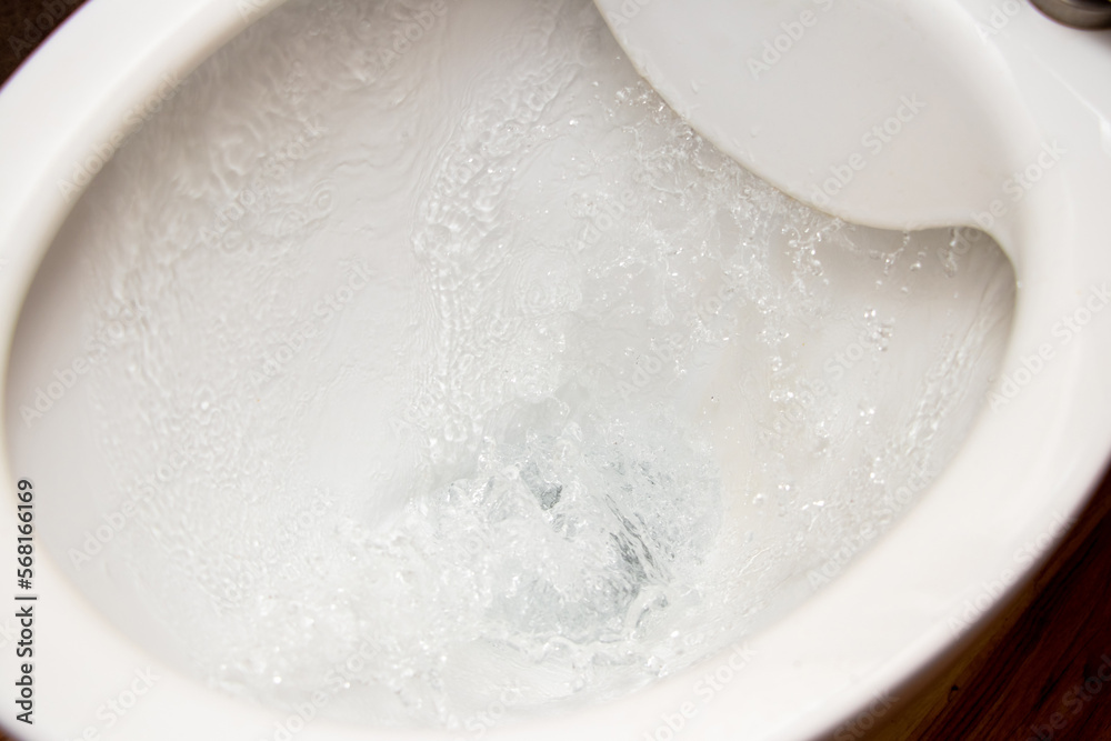 Toilet while flushing urine with water. A stream of water in the toilet ...