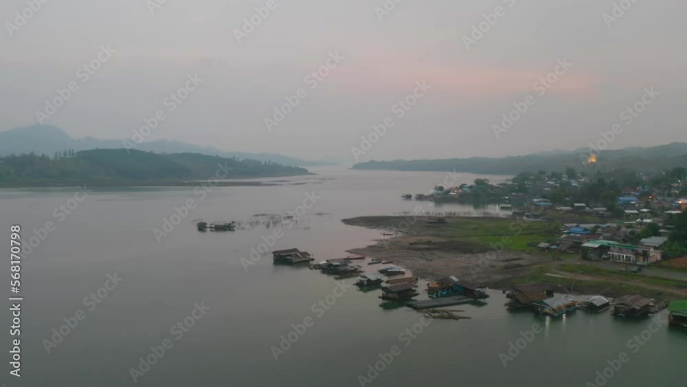 Aerial top view of residential local floating houses in Mon village, nature trees with lake or river, Kanchanaburi, Thailand in urban city town in Asia, buildings. Aerial top view of residential local floating houses in Mon village, nature trees with lake or river, Kanchanaburi, Thailand in urban city town in Asia, buildings.