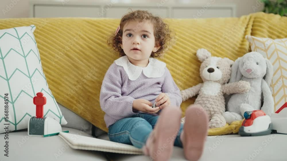 Adorable hispanic girl sitting on sofa with teddy bear at home Adorable hispanic girl sitting on sofa with teddy bear at home
