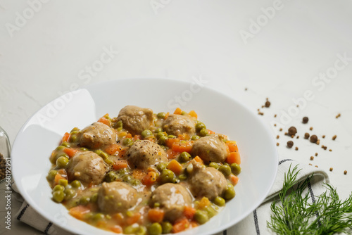 Plate of meatballs in gravy with vegetbales