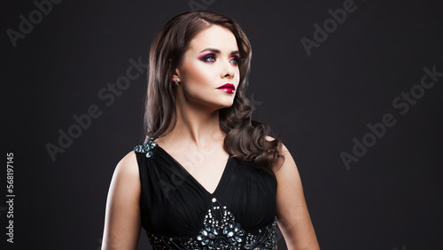 Gorgeous young brunette in a chic evening look. Scarlet lips and eye shadow, wave hair styling