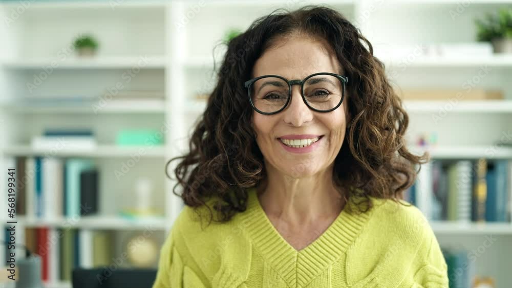 Middle age hispanic woman teacher smiling confident standing at library university Middle age hispanic woman teacher smiling confident standing at library university