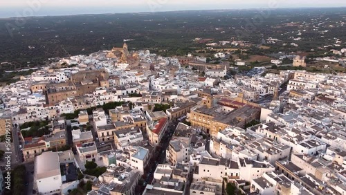 Aerial panoramic drone footage of Ostuni - La Citta Bianca (white city), Puglia, Italy at sunset. View of Cathedral, main square, the medieval historic old town landmark tourist destination from above
