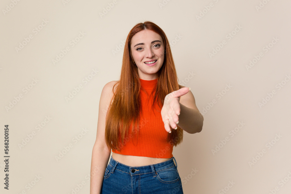 Young red hair woman isolated stretching hand at camera in greeting gesture. Young red hair woman isolated stretching hand at camera in greeting gesture.