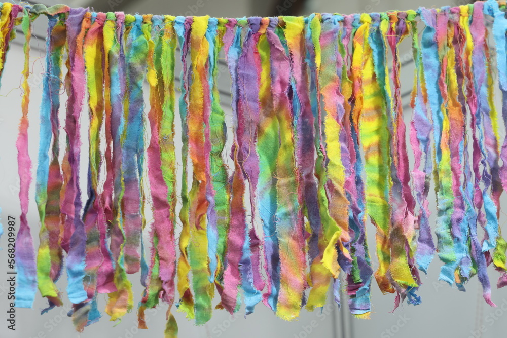 Colorful ribbons of different colors hang in a row on the wall. Colorful abstract background. Wall of colorful silk ribbons.