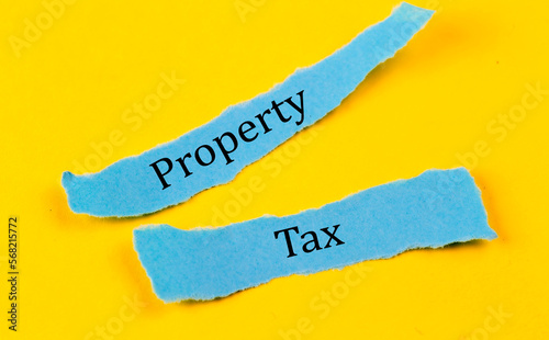 PROPERTY TAX text on a blue pieces of paper on yellow background, business concept photo