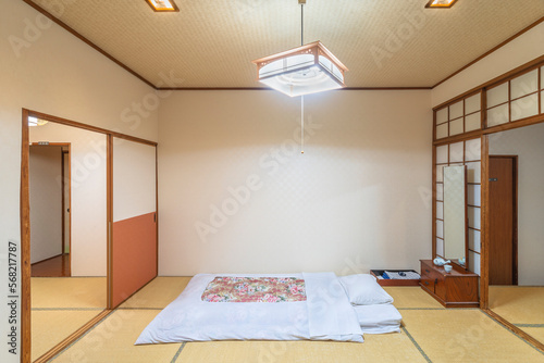 A typical traditional Japanese bedroom characterized by tatami mats, shoji doors, fusuma walls, futon mattress and minimalist decorations, creating a peaceful and serene atmosphere. photo