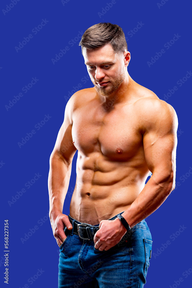 Handsome man with big muscles, posing at the camera in studio, man looking down. Portrait of an athletic model man in jeans. Closeup.