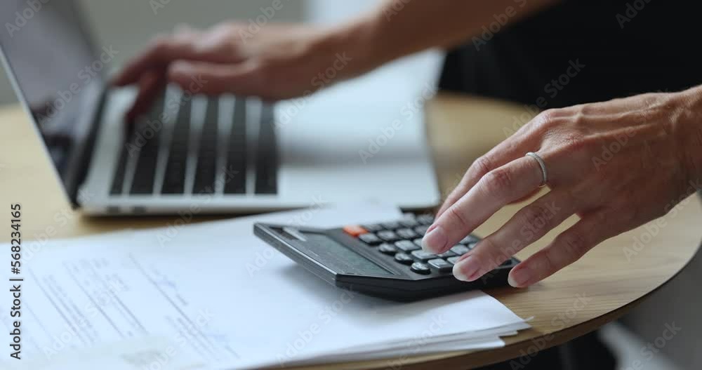 Family budget management, paying bills and taxes through e-banking application, using internet and modern tech, finances. Unknown female hands using calculator and laptop do accountancy job, close up Family budget management, paying bills and taxes through e-banking application, using internet and modern tech, finances. Unknown female hands using calculator and laptop do accountancy job, close up