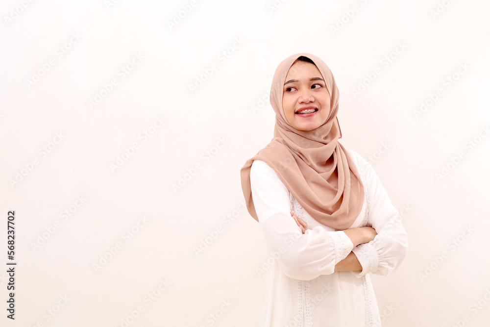 Portrait of young asian muslim woman standing with folded hands while looking at blank space Portrait of young asian muslim woman standing with folded hands while looking at blank space