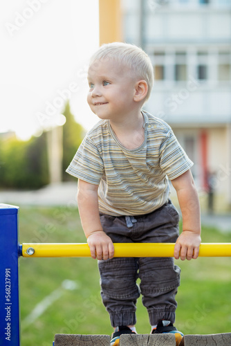 Little boy climbs on playground. Cute smiling kid playing outdoors. Concept of kindergarten