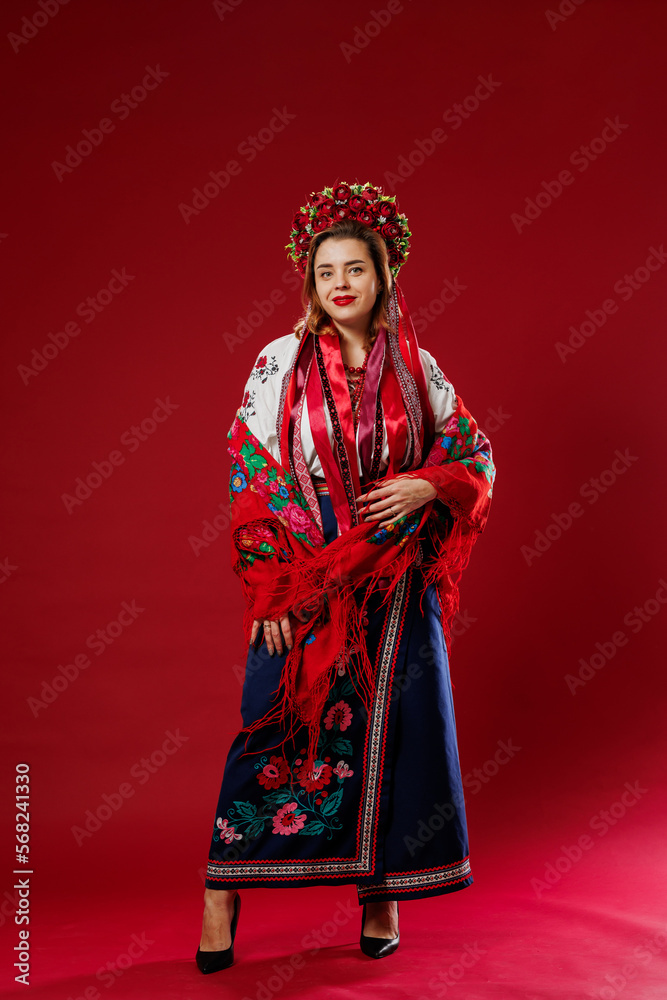 Portrait of ukrainian woman in traditional ethnic clothing and floral red wreath on viva magenta studio background. Ukrainian national embroidered dress call vyshyvanka. Pray for Ukraine