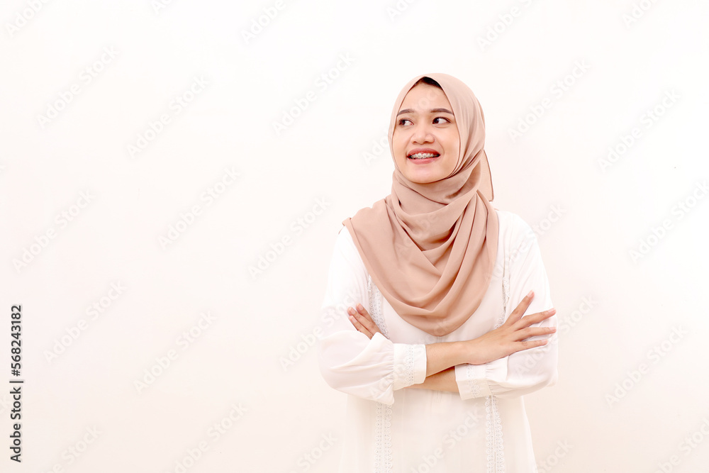 Portrait of young asian muslim woman standing with folded hands while looking sideways on copyspace Portrait of young asian muslim woman standing with folded hands while looking sideways on copyspace