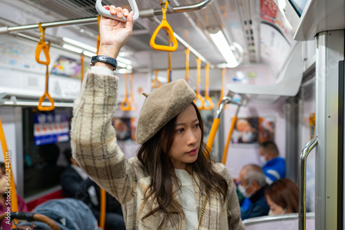 Happy Asian woman tourist enjoy and fun outdoor lifestyle travel Japan by subway transportation on autumn holiday vacation. Attractive girl traveler travel on train with looking out of the window.