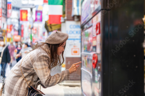 Tableau sur toile Happy Asian woman choosing and buying drinks on snack and beverage vending machine while shopping at shibuya, Tokyo, Japan