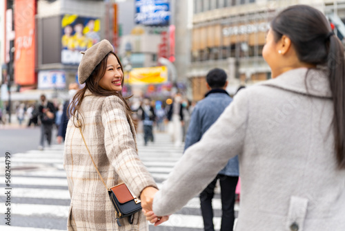 Wall Mural Asian woman friends crossing street crosswalk with crowd of people during shopping at Shibuya, Tokyo, Japan in autumn