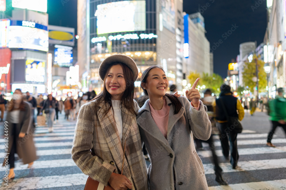 Asian woman shopping and crossing street crosswalk with crowd of people at Shibuya, Tokyo, Japan at night. Happy girl friends enjoy and fun outdoor lifestyle travel in the city in autumn vacation. Asian woman shopping and crossing street crosswalk with crowd of people at Shibuya, Tokyo, Japan at night. Happy girl friends enjoy and fun outdoor lifestyle travel in the city in autumn vacation.
