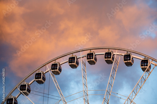 The row of Ferris wheel cabins against the backdrop of beautiful sunset red clouds.