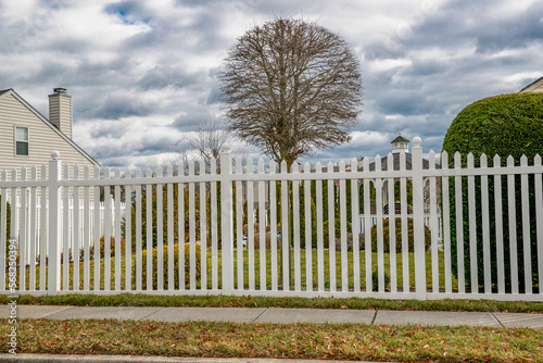 a new white vinyl fence by a grass area with trees behind it green property modern