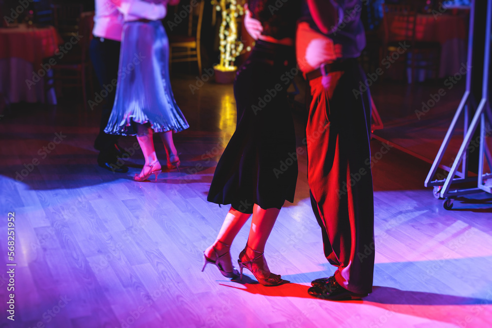 Couples dancing traditional latin argentinian dance milonga in the ballroom on a festival, tango studio, salsa, bachata and kizomba lesson in the red and purple lights, rehearsal in the dance class