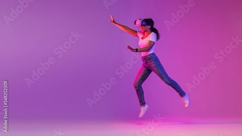 Joyful Black Woman Wearing Vr Glasses Jumping On Air In Neon Light