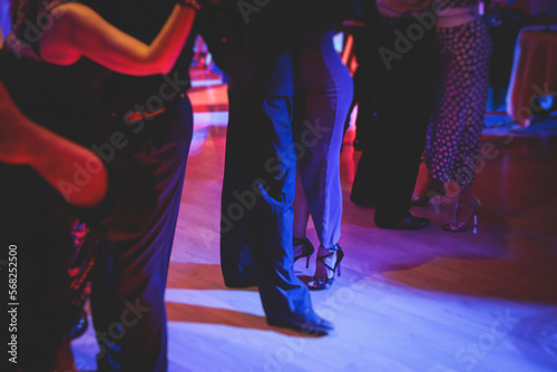 Couples dancing traditional latin argentinian dance milonga in the ballroom on a festival, tango studio, salsa, bachata and kizomba lesson in the red and purple lights, rehearsal in the dance class