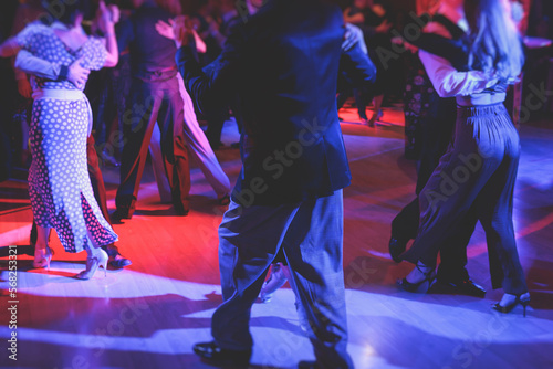 Couples dancing traditional latin argentinian dance milonga in the ballroom on a festival, tango studio, salsa, bachata and kizomba lesson in the red and purple lights, rehearsal in the dance class