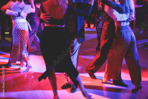 Couples dancing traditional latin argentinian dance milonga in the ballroom on a festival, tango studio, salsa, bachata and kizomba lesson in the red and purple lights, rehearsal in the dance class