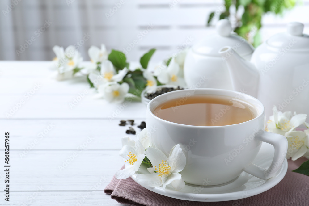 Cup of tea and fresh jasmine flowers on white wooden table. Space for text Cup of tea and fresh jasmine flowers on white wooden table. Space for text