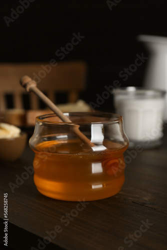 Jar with honey, milk, bread and butter on wooden table