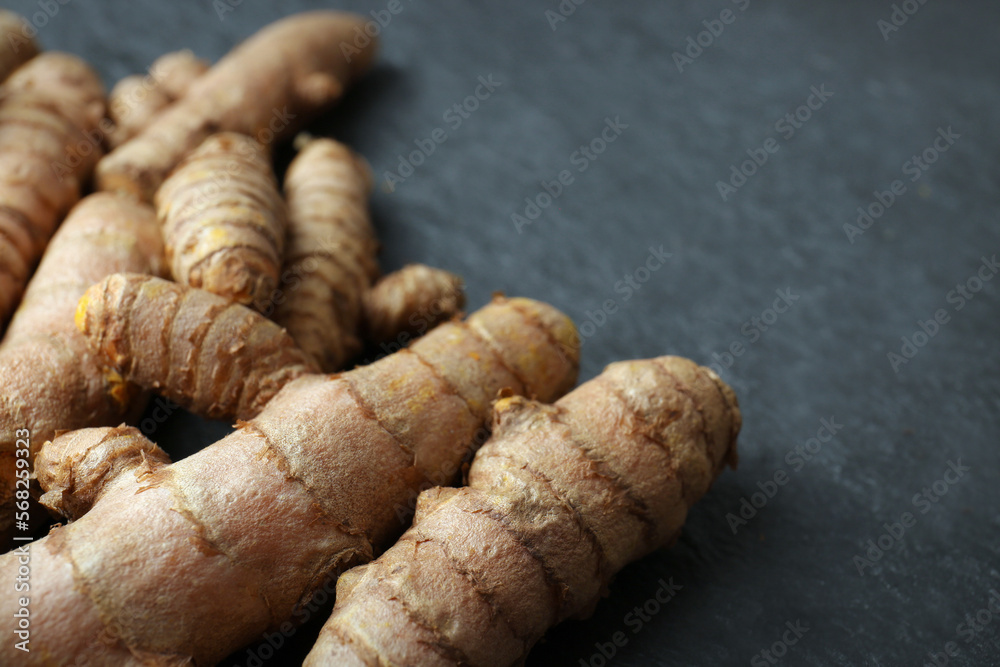 Many raw turmeric roots on black textured table, closeup. Space for text Many raw turmeric roots on black textured table, closeup. Space for text