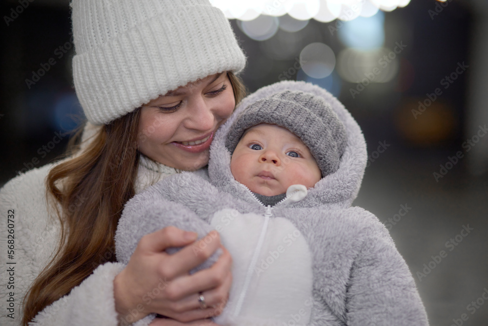 young woman with a baby in her arms walking around the city. mom and son are walking in cold weather, dressed in trendy warm clothes. Mom gently hugs her child. young woman with a baby in her arms walking around the city. mom and son are walking in cold weather, dressed in trendy warm clothes. Mom gently hugs her child.