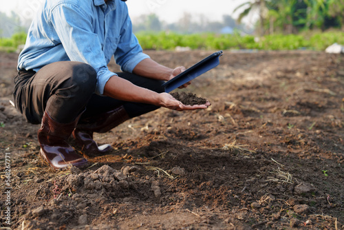 Asian farmers check soil quality in fields before tillage. Prepare the soil for planting and fertilizing. to increase productivity Agriculture concept, holding tablet pc