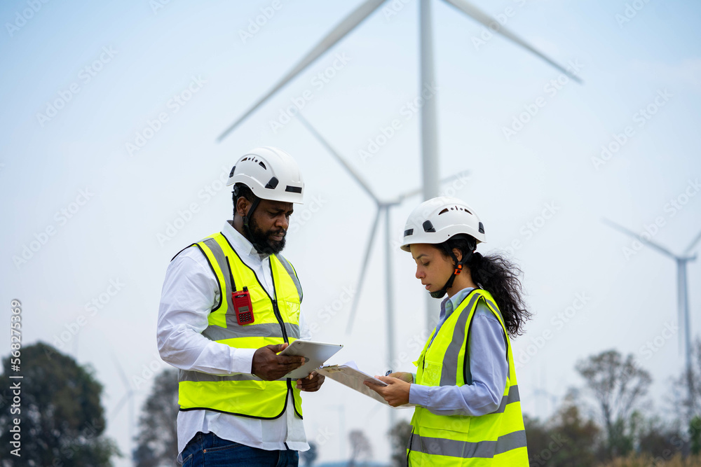 Engineer male and female on wind turbine farm. Two engineers discussed the plan for the maintenance of wind turbines. Engineer male and female on wind turbine farm. Two engineers discussed the plan for the maintenance of wind turbines.