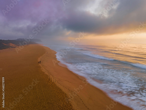 Summer sunrise fog descends over the headland at the beach