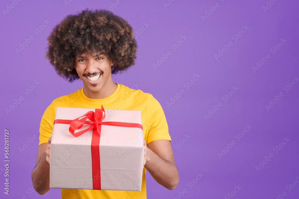 Happy african man smiling at camera while giving a gift Happy african man smiling at camera while giving a gift