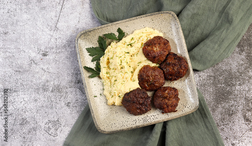 Mashed potatoes with cutlets and herbs on a square  plate on a dark background. Top view, flat lay