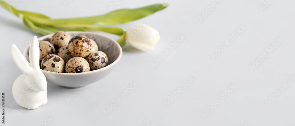 Bowl with Easter eggs, bunny and tulip flower on light background with space for text Bowl with Easter eggs, bunny and tulip flower on light background with space for text