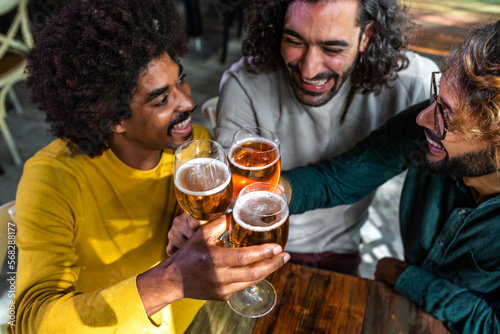High angle view of happy male friends in a bar enjoying drinks together toasting with beer  having fun.