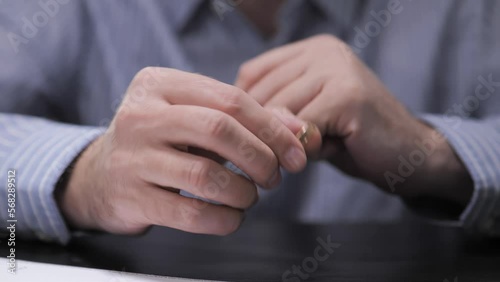 Divorce. The end of the relationship. The man takes off his wedding ring and signs the divorce documents at the lawyer's office.