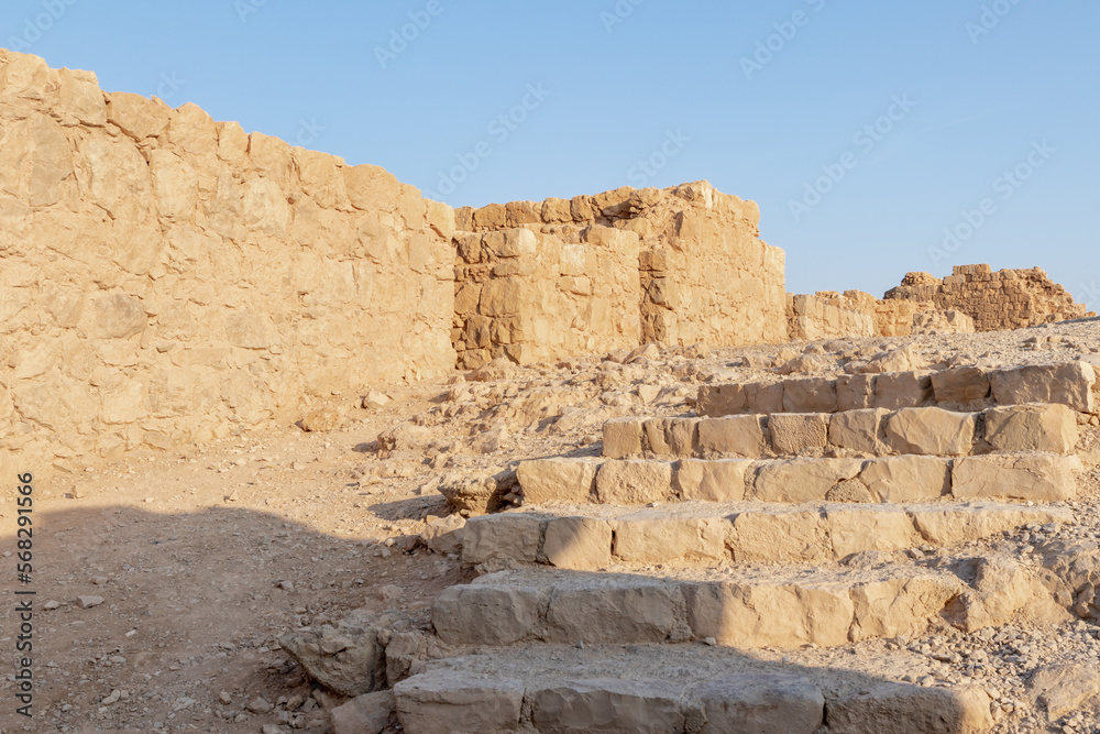 The remains  of internal buildings in the rays of the rising sun in the ruins of the fortress of Masada - is a fortress built by Herod the Great on a cliff-top off the coast of the Dead Sea, Israel