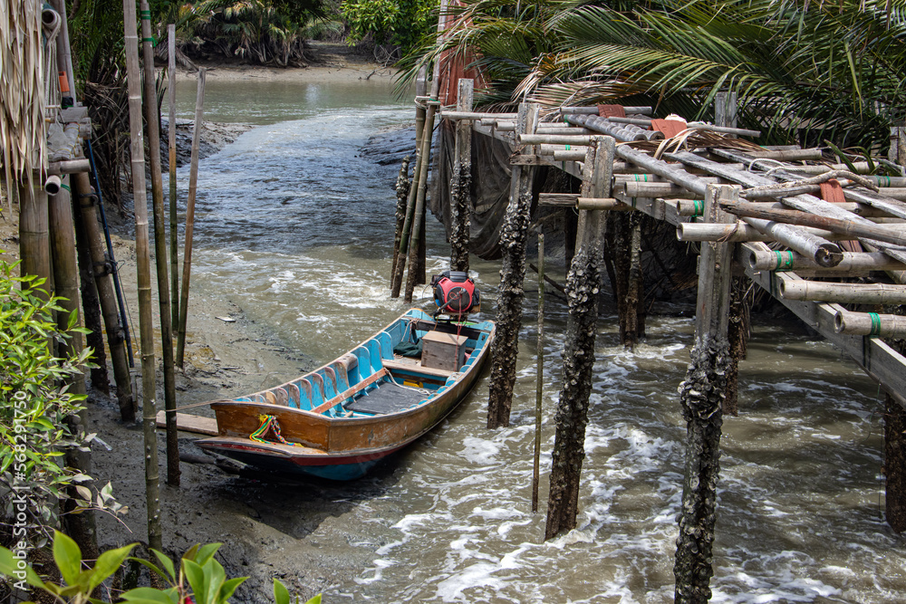 An wooden boat with the engine is moored in the water canal, Thailand