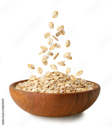 Konstfotografi uncooked oatmeal falling in wooden bowl isolated on white
