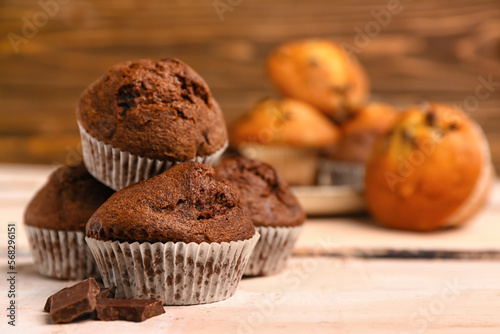Delicious chocolate muffins on white wooden table