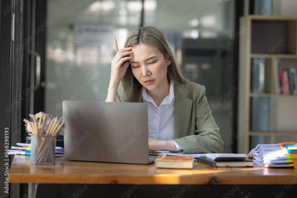 Asian businesswoman are stressed and tired from work sitting at desk in the office, feeling sick at work, stress from work.	