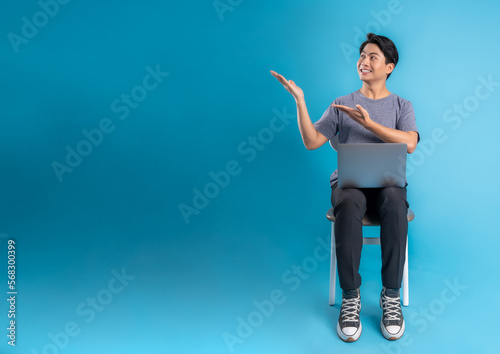 Full body youngAsian  using laptop and posing on blue background photo
