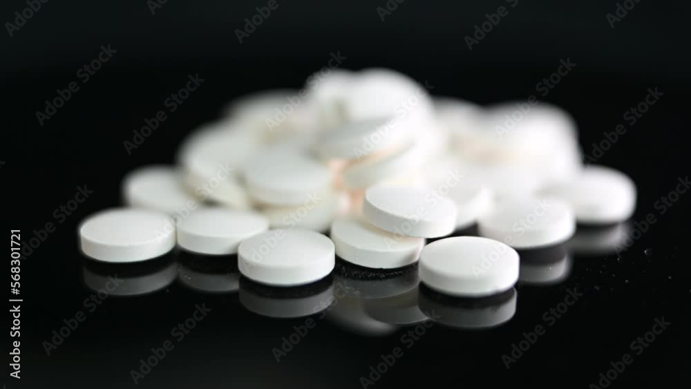 A pile of generic white pills in on a reflective surface A pile of generic white pills in on a reflective surface
