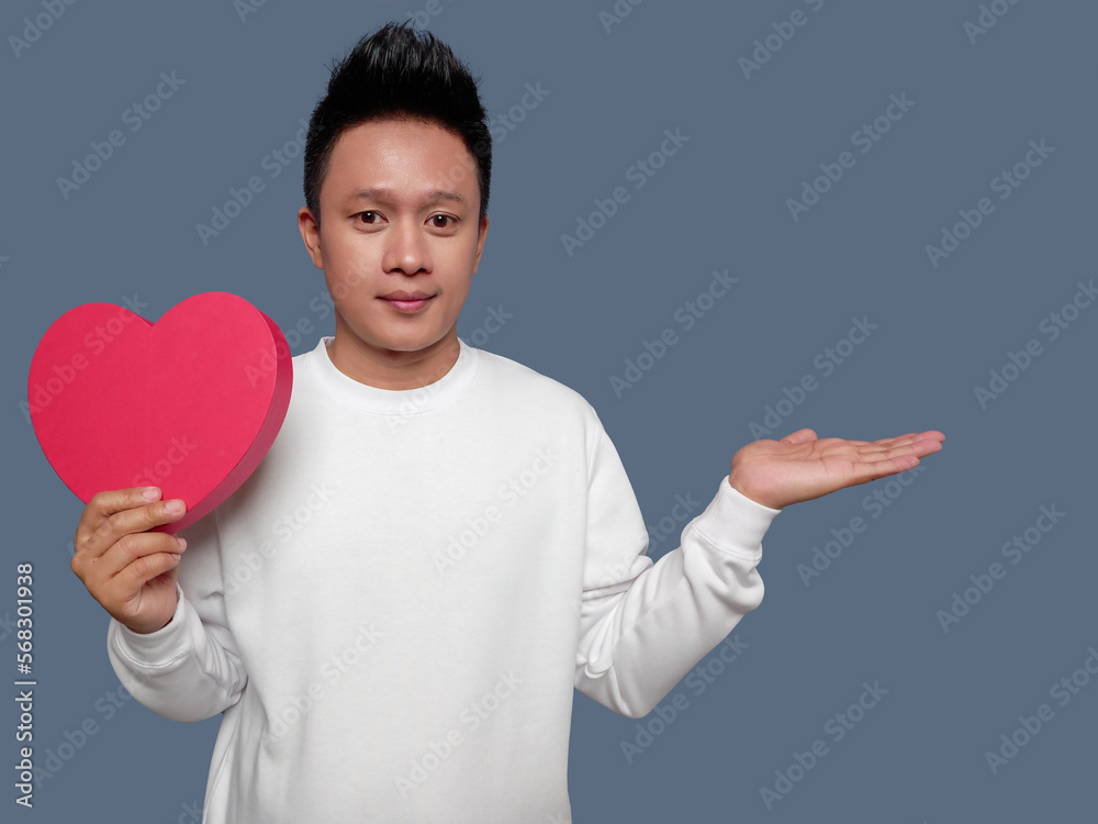 Handsome man holding red heart shape and comparing Handsome man holding red heart shape and comparing