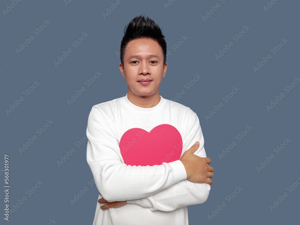 Handsome man hugging red heart shape isolated on plain background Handsome man hugging red heart shape isolated on plain background